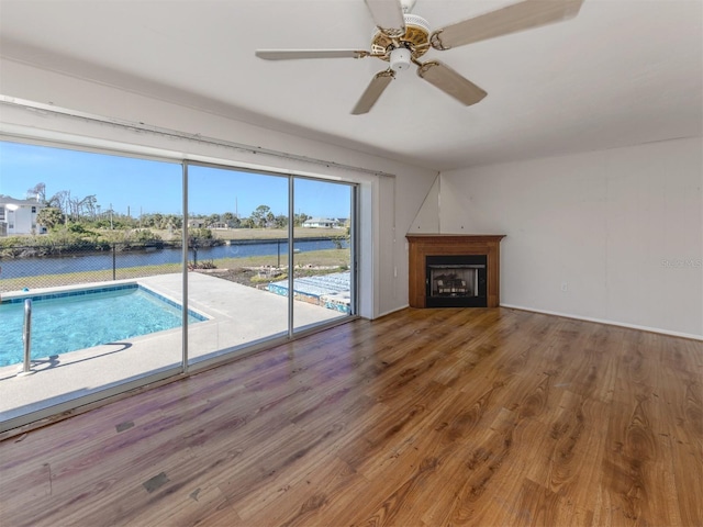 unfurnished living room with a water view and ceiling fan