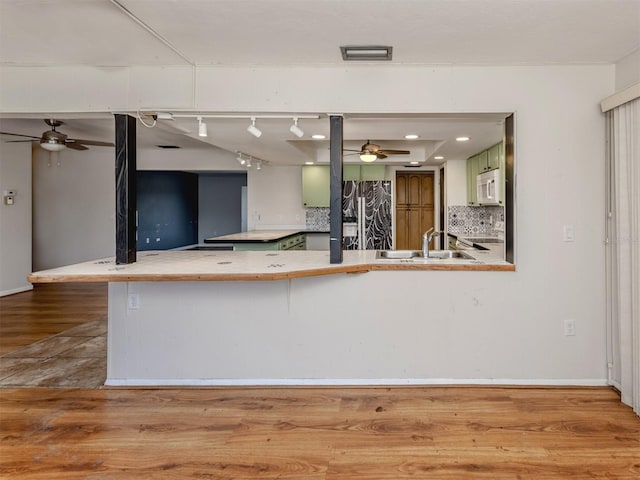 kitchen featuring sink, tasteful backsplash, fridge, kitchen peninsula, and light hardwood / wood-style floors