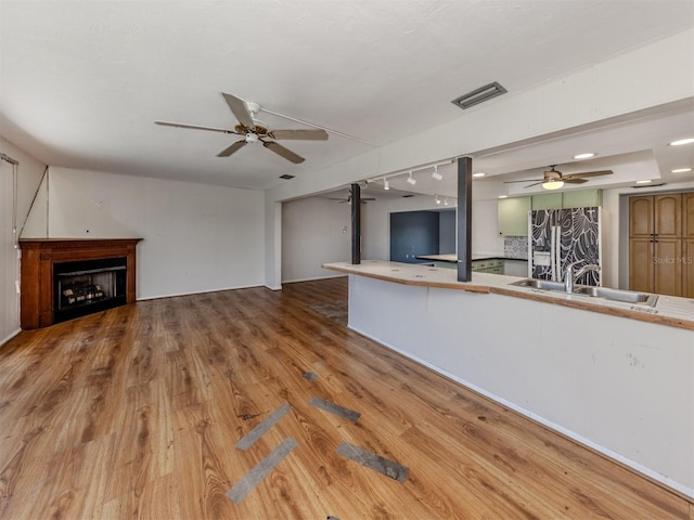 unfurnished living room featuring sink, hardwood / wood-style floors, and ceiling fan