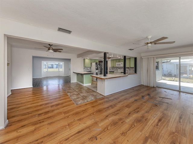 kitchen with ceiling fan, kitchen peninsula, light hardwood / wood-style floors, and decorative backsplash