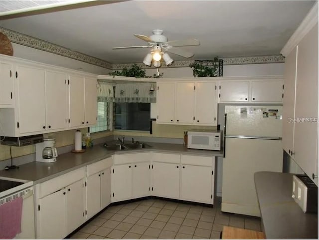 kitchen featuring white appliances, sink, ceiling fan, light tile patterned floors, and white cabinetry