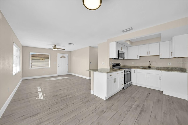 kitchen with kitchen peninsula, stainless steel appliances, ceiling fan, stone countertops, and white cabinets