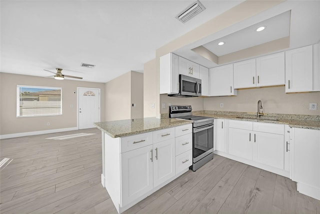 kitchen with kitchen peninsula, appliances with stainless steel finishes, sink, light hardwood / wood-style flooring, and white cabinetry