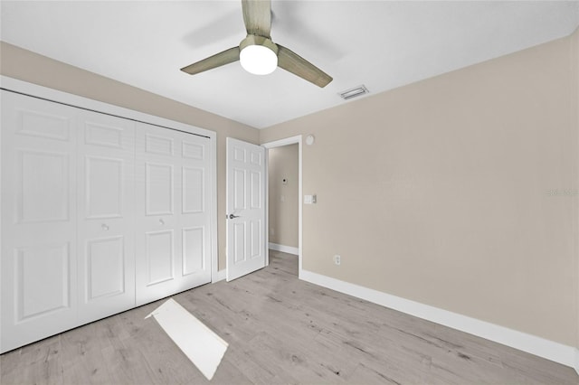 unfurnished bedroom featuring ceiling fan, a closet, and light wood-type flooring