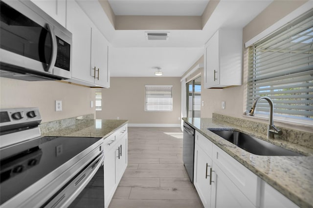 kitchen featuring light stone counters, sink, white cabinets, and appliances with stainless steel finishes