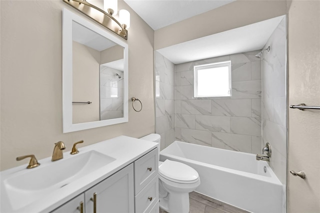 full bathroom featuring tiled shower / bath combo, toilet, and vanity