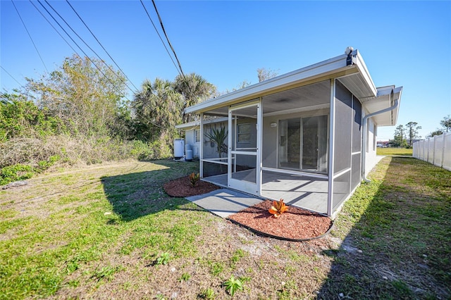 back of house featuring a lawn and a sunroom