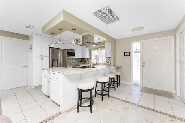 kitchen with decorative backsplash, white cabinetry, kitchen peninsula, and stainless steel appliances