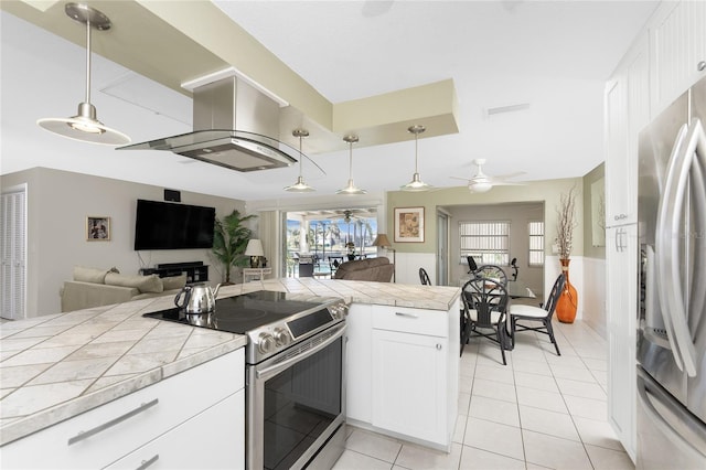 kitchen featuring ceiling fan, white cabinets, stainless steel appliances, and decorative light fixtures