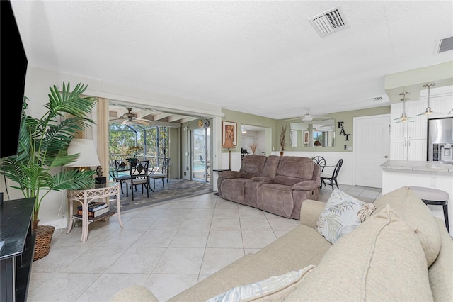 living room featuring light tile patterned floors, a textured ceiling, and ceiling fan