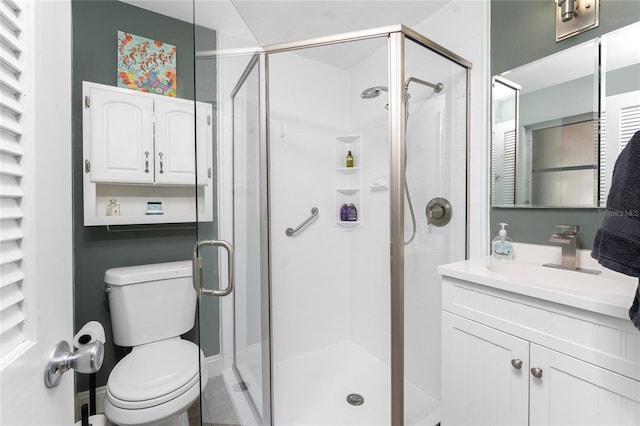 bathroom featuring a shower with door, vanity, and toilet