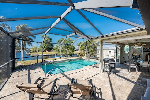 view of pool with a lanai, grilling area, a patio, and a water view