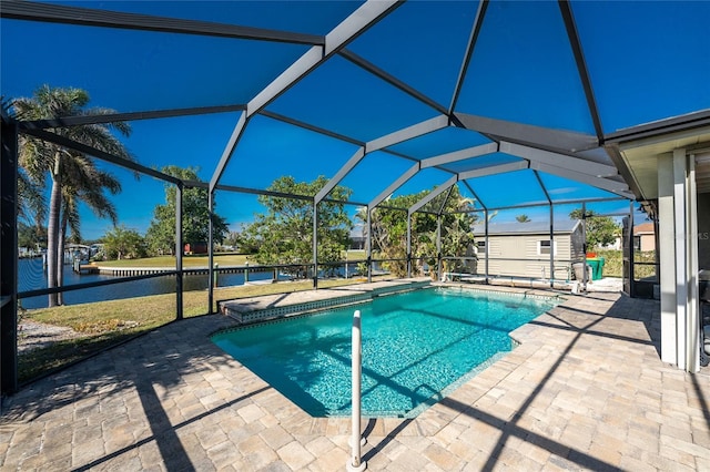 view of pool with a patio area, a lanai, a water view, and a storage shed