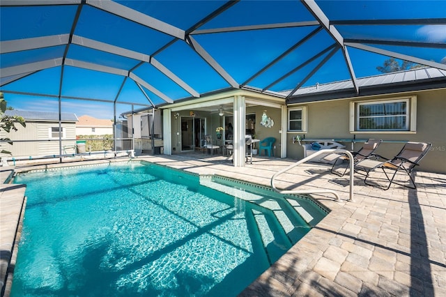 view of swimming pool with glass enclosure, ceiling fan, and a patio area