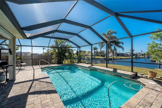 view of swimming pool featuring glass enclosure, a water view, and a patio