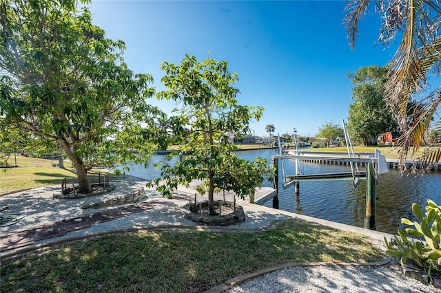 view of dock with a lawn and a water view