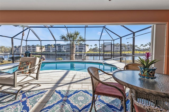 view of pool featuring glass enclosure, a patio area, and a water view