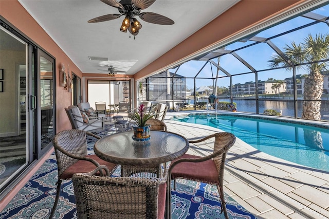 view of swimming pool with glass enclosure, a patio area, a water view, and ceiling fan