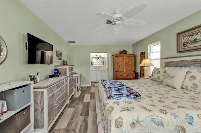 bedroom with ceiling fan, a textured ceiling, ensuite bath, and hardwood / wood-style floors