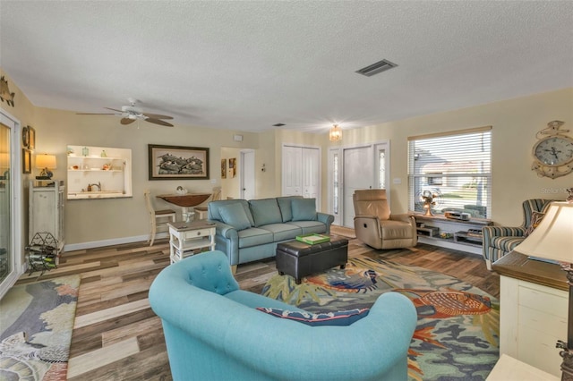 living room with ceiling fan, wood-type flooring, and a textured ceiling