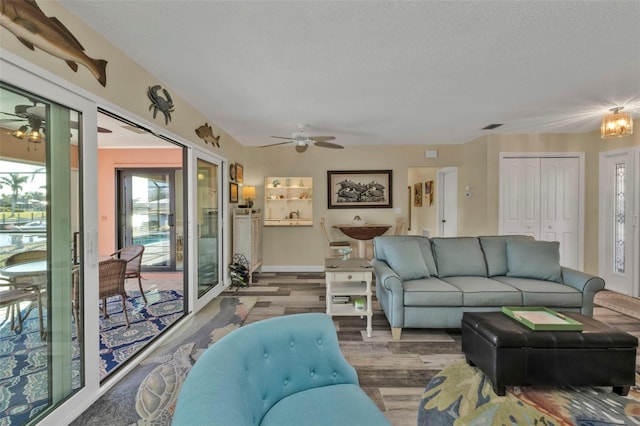 living room featuring ceiling fan, wood-type flooring, and a textured ceiling