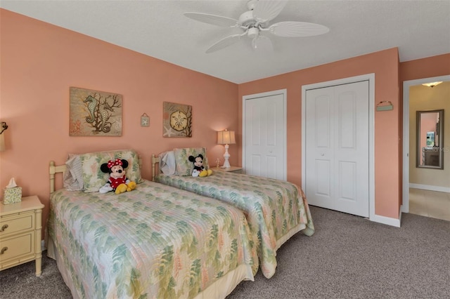 bedroom featuring dark colored carpet, multiple closets, and ceiling fan