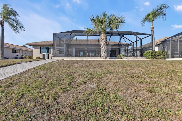 rear view of property with a lanai and a lawn