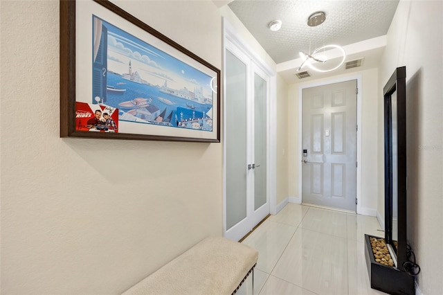 interior space featuring french doors, a textured ceiling, a chandelier, and light tile patterned flooring