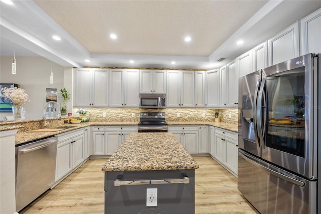 kitchen with pendant lighting, decorative backsplash, white cabinetry, stainless steel appliances, and light stone counters