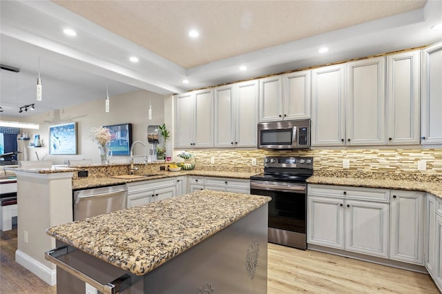 kitchen featuring light stone countertops, a kitchen island, stainless steel appliances, sink, and backsplash