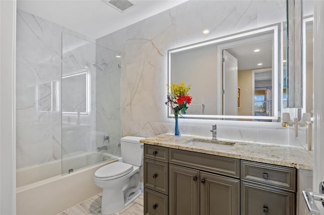 full bathroom featuring toilet, tile walls, tiled shower / bath, and vanity