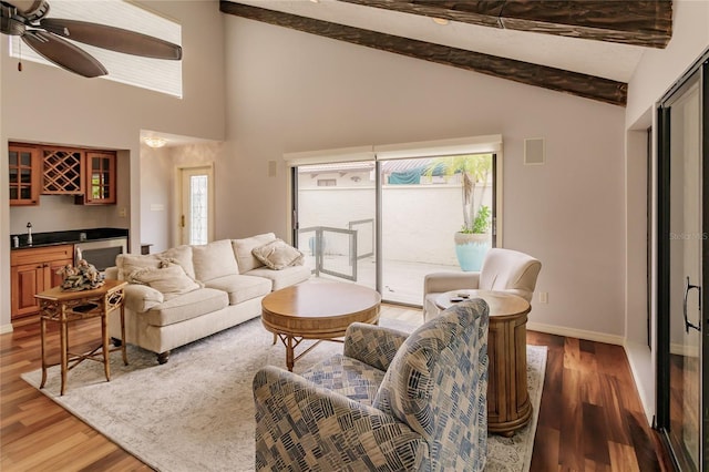 living room with vaulted ceiling with beams, dark hardwood / wood-style flooring, wet bar, and ceiling fan