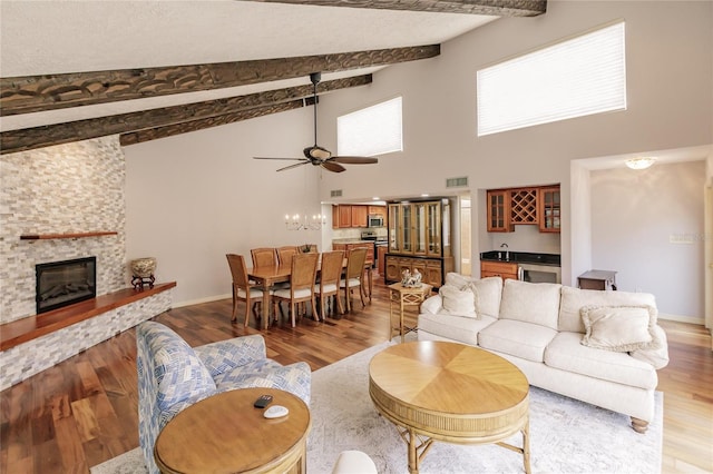 living room featuring beamed ceiling, light wood-type flooring, and ceiling fan