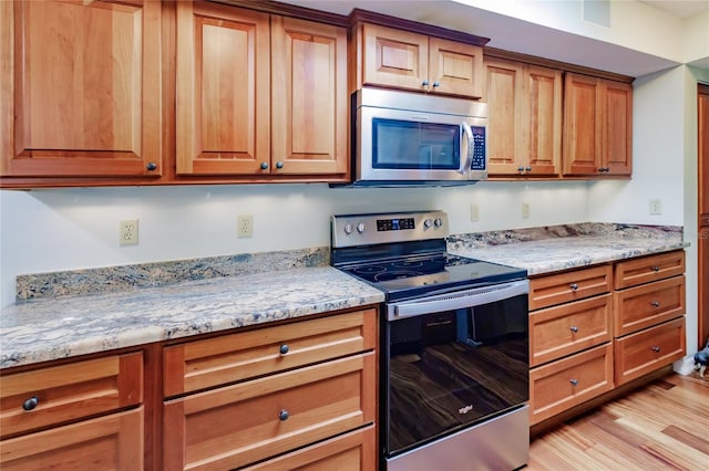 kitchen with light stone counters, stainless steel appliances, and light hardwood / wood-style flooring