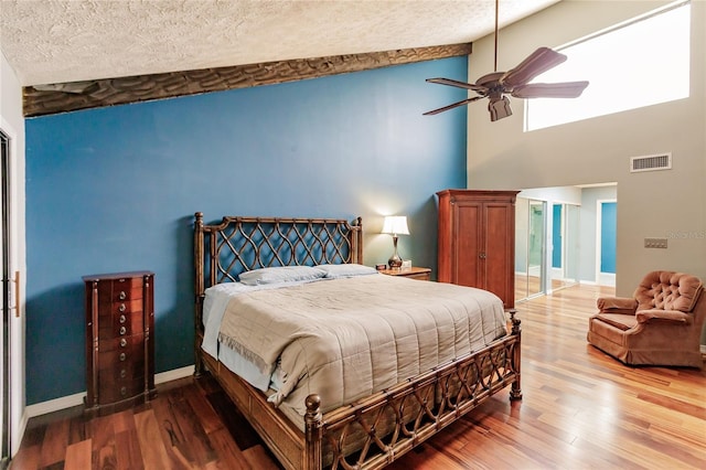 bedroom with ceiling fan, wood-type flooring, and high vaulted ceiling