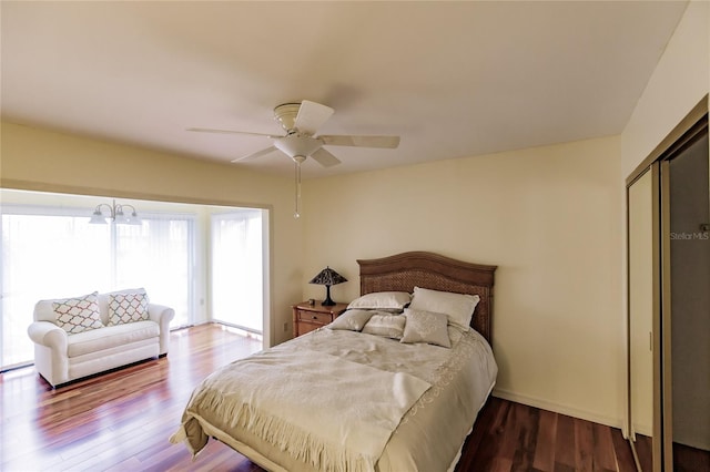 bedroom featuring access to exterior, hardwood / wood-style floors, ceiling fan with notable chandelier, and a closet