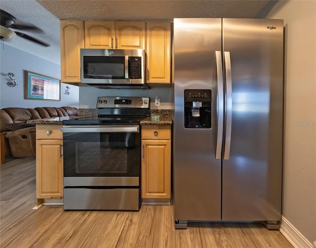 kitchen with light brown cabinetry, light wood-type flooring, a textured ceiling, and appliances with stainless steel finishes