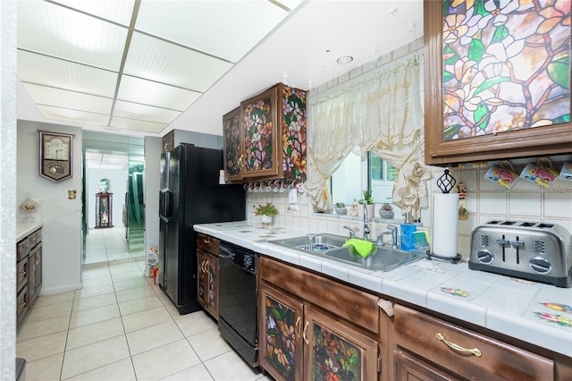 kitchen featuring tile countertops, black appliances, sink, light tile patterned floors, and tasteful backsplash