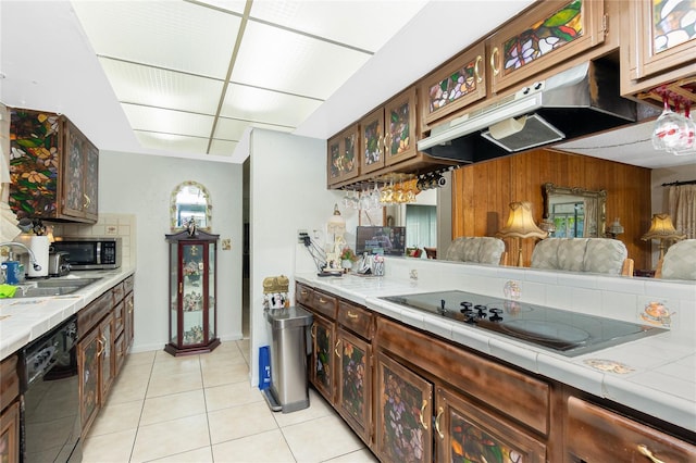 kitchen featuring black appliances, tile counters, light tile patterned flooring, and dark brown cabinets