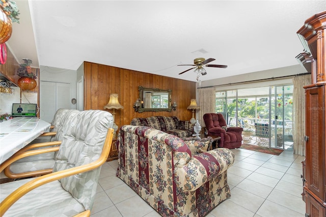 tiled living room featuring ceiling fan and wood walls