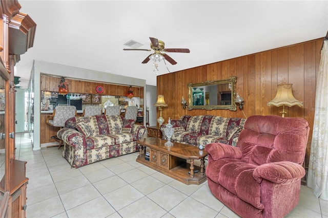 living room with light tile patterned floors, ceiling fan, and wooden walls