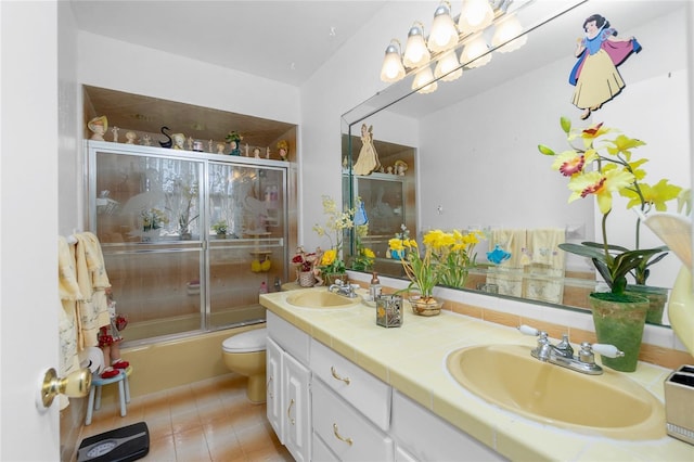 full bathroom with tile patterned floors, vanity, toilet, and bath / shower combo with glass door