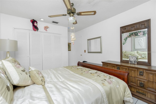 bedroom featuring ceiling fan, a closet, light tile patterned floors, and a textured ceiling