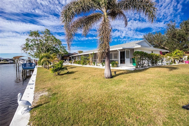 view of yard with a sunroom, a water view, and a dock