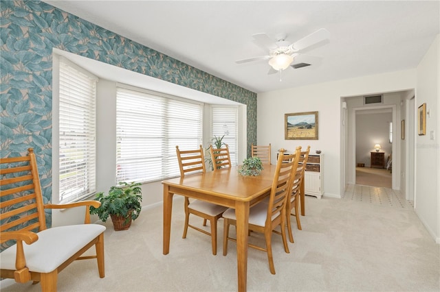 dining space featuring ceiling fan and light colored carpet