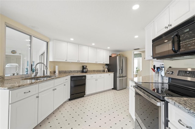 kitchen featuring white cabinetry, sink, light stone counters, and black appliances