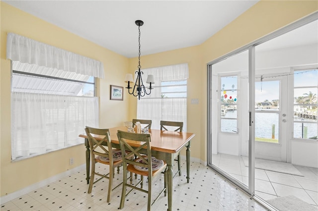 dining space featuring a water view, french doors, and an inviting chandelier