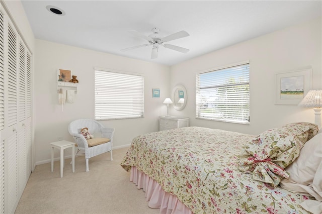 bedroom with ceiling fan, light colored carpet, and a closet