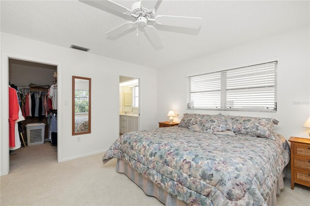 bedroom with a spacious closet, ensuite bathroom, ceiling fan, a closet, and multiple windows