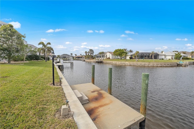 view of dock featuring a lawn and a water view